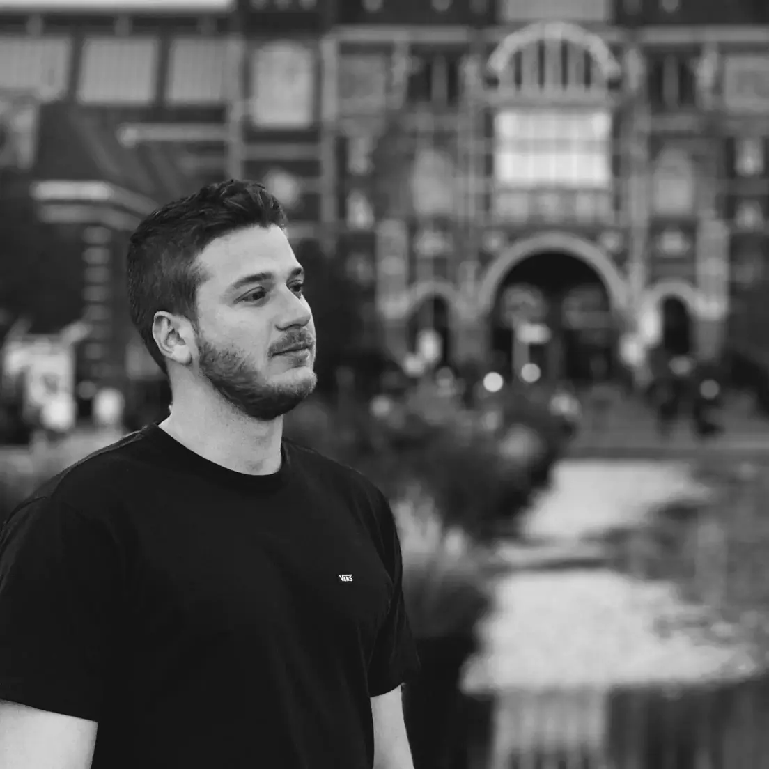 Photo of Vinicius Vicentini, looking up and behind him is the Rijksmuseum, in Amsterdam
