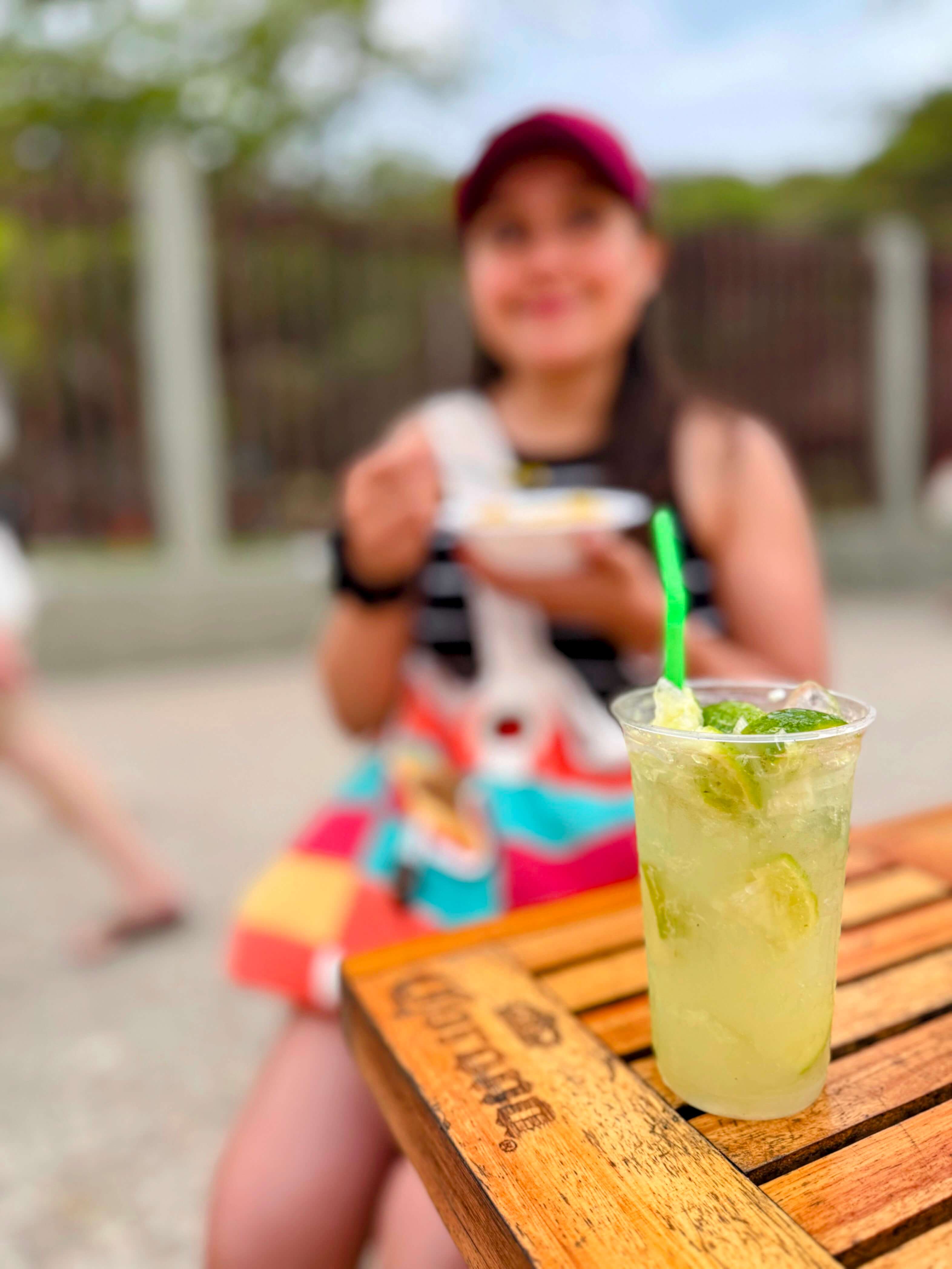 Copo de caipirinha bem gelado em cima da mesa e em frente a praia de Ipanema
